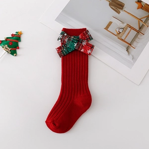 Detailed view of red Christmas baby socks with a festive red and green plaid bow detail