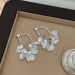 Detailed view of silver sequin petal tassel earrings on a velvet jewelry tray