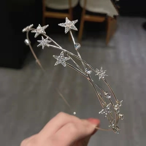 Macro shot of silver celestial headband with layered metal stars and pearl accents