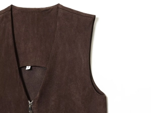 Détail de la texture du daim marron foncé et des coutures de poche sur la veste
