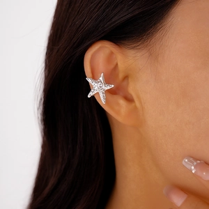 Macro shot of silver starfish ear cuff with detailed metallic spiral texture on ear