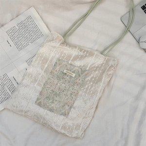 Flat lay of beige velvet tote with lace embroidery and mint green straps on cotton linen