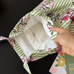 Detail view showing interior white zipper pocket and floral lining of the cotton tote bag