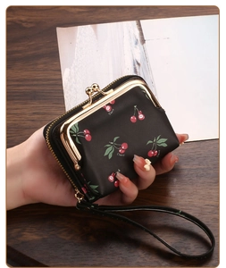 Detail of black cherry print card holder with gold clasp, zipper and wrist strap