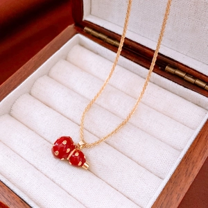 Close-up of 18k gold plated red calabash pendant on necklace in a wooden jewelry box