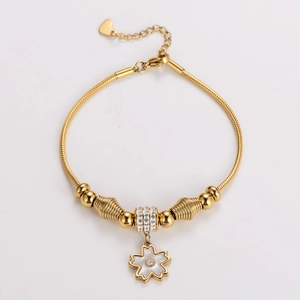 Close-up of gold flower charm bracelet with crystal beads on a snake chain