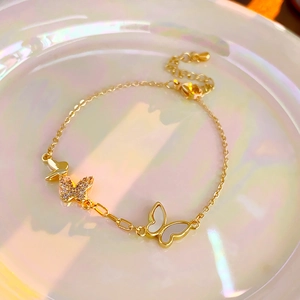 Detail of gold plated butterfly bracelet with zircon inlay and white mother of pearl