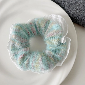 Close-up of knit scrunchie with colorful yarn stripes and white lace trim edge