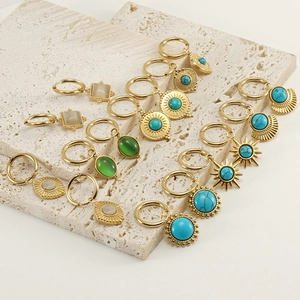 Détail de boucles d'oreilles bohèmes dorées avec turquoise et pendentifs géométriques
