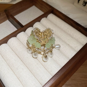 Detailed close-up of golden hair pin with green flowers and teardrop pearl tassels