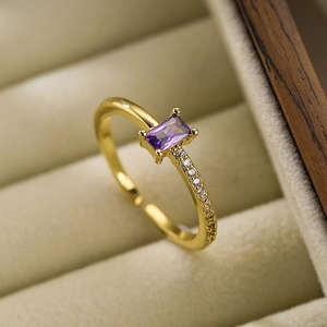 Detail of elegant gold ring with rectangular purple gemstone and side zircon accents