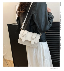 Chic cream leather rectangular crossbody bag with dual buckles shown on a female model