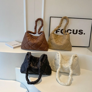 Quilted puffer tote bags in brown, khaki, black and white displayed in a minimalist room