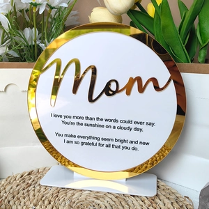 Detail of round acrylic plaque with gold mirror Mom lettering on a woven mat