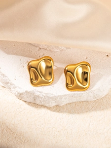 Boucles d'oreilles géométriques dorées irrégulières sur présentoir en pierre et soie