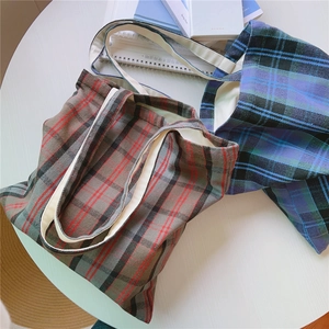 Draufsicht auf Retro-Karo-Stofftaschen in Braun und Blau mit cremefarbenen Griffen am Tisch