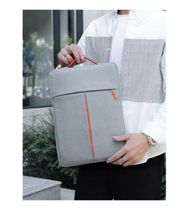 Slim grey laptop sleeve with orange accents held by model in outdoor office setting