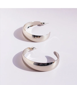 Detailed macro view of wide C-shaped silver hoop earrings with a mirror polished finish