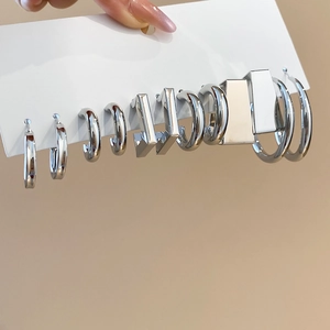 Detail shot of various silver geometric C-shape and square hoop earrings on card
