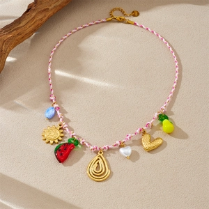 Détail d'un collier bohème en corde tressée avec pendentifs cœur, fruits et soleil