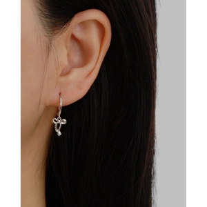 Close-up of s925 silver bow ribbon hoop earrings worn by a model in a minimal setting