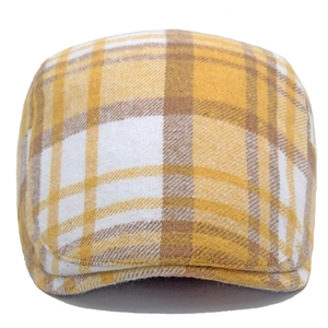 Close-up of yellow and brown plaid patterns on a woolen winter flat cap for men