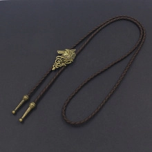 Detailed view of an antique brass wolf head slide on a brown braided leather bolo tie