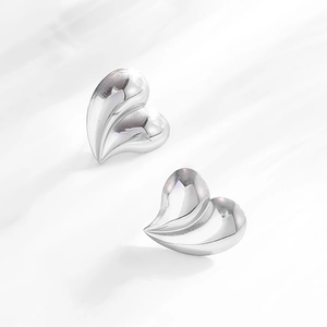 Macro detail of oversized heart-shaped silver earrings in polished stainless steel