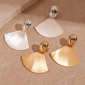 Geometric fan-shaped brushed metal earrings in gold and silver finishes on stone