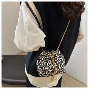Detail of leopard print bucket bag with gold chain strap and pearl charm accent