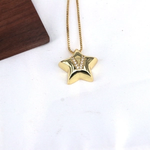 Detailed macro view of gold star pendant with crystal V initial on a thin snake chain
