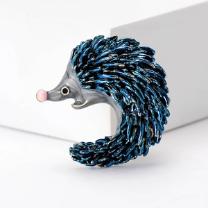 Detailed view of blue enamel hedgehog brooch with polished gray metal and pink nose