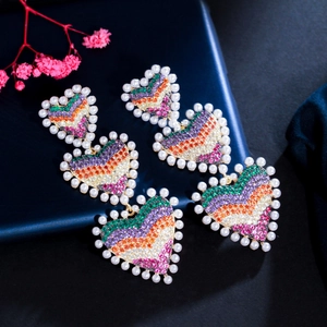 Gros plan de boucles d'oreilles triple cœur avec zircons colorés et bordure de perles