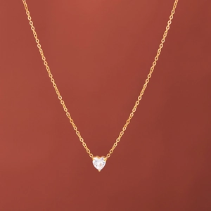 Macro view of gold-plated heart pendant with transparent cubic zirconia and fine chain