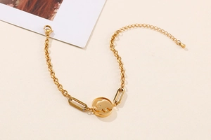 Detail of a gold elephant charm bracelet with geometric links on a beige background