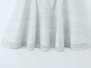 Detail view of the white polka dot chiffon dress hemline with soft flowy fabric texture
