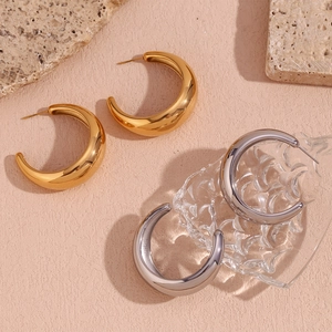 Polished gold and silver C-shaped chunky earrings displayed with natural stone texture
