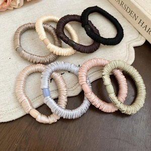 Detailed view of colorful silk satin hair ties in various elegant shades on a wooden surface