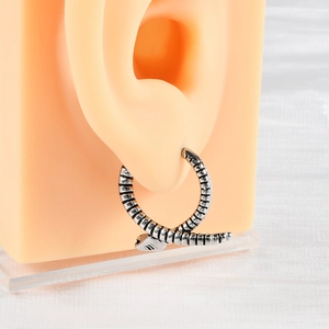 Detailed close-up of a vintage punk snake earring in antique silver on a silicone ear model