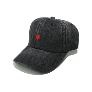 Close-up of red heart embroidery on dark grey denim baseball cap with washed texture