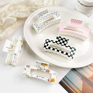 Detailed view of hair claw clips with checkered and floral prints in a ceramic bowl