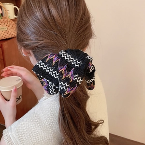 Détail d'un chouchou ethnique en maille tricotée avec broderies colorées sur cheveux