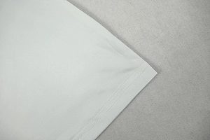 Detailed close-up showing double-needle stitching on white knitted dress hemline
