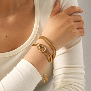 Two-piece 18k gold plated snake chain and knot bracelet set on a female wrist