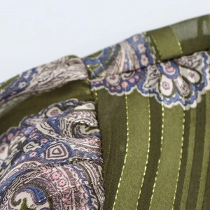 Close-up of metallic gold thread embroidery on green paisley print fashion shirt
