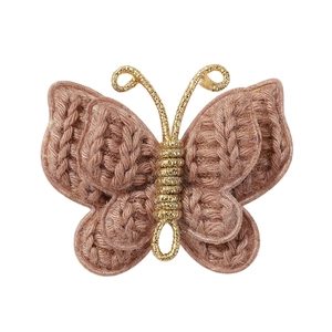 Macro detail of hand-knitted butterfly hair clip with gold metallic wire accents