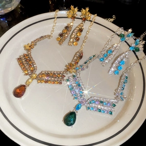 Detail of floral necklace and teardrop crystal earrings in gold and silver finishes
