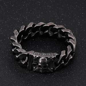 Detailed macro view of vintage gunmetal cuban link bracelet with skull relief buckle