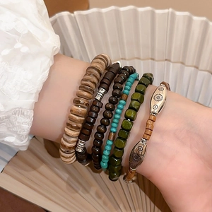 Close-up of bohemian layered beaded bracelet with wooden beads and ethnic floral metal charms