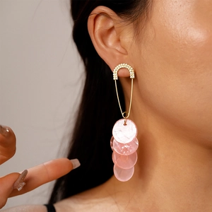 Detail of safety pin earrings with sparkling crystals and hanging pink shell discs